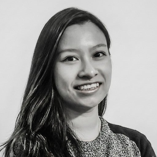 Smiling woman with long dark hair wearing a dark top, shown in a black and white portrait.